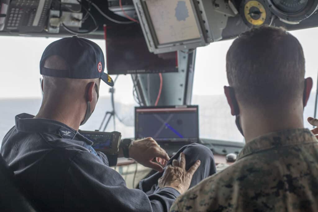 PHILIPPINE SEA (Aug. 26, 2020) Capt. Luke Frost, commanding officer of amphibious assault ship USS America (LHA 6), tries on and tests the Android Tactical Assault Kit (ATAK) while Capt. Jacob Rhine, 5th Air Naval Gunfire Liaison Company detachment officer-in-charge, briefs the system's capabilities. The ATAK is used to plan and coordinate aircraft and personnel movements. America, flagship of the America Amphibious Ready Group (ARG), 31st MEU team, is operating in the U.S. 7th Fleet area of operation to enhance interoperability with allies and partners and serve as a ready response force to defend peace and stability in the Indo-Pacific region. The America ARG, 31st MEU team remains the premier crisis response force in the region despite the unique challenges caused by the COVID-19 pandemic. (U.S. Marine Corps photo by Sgt. Dominic Clay)